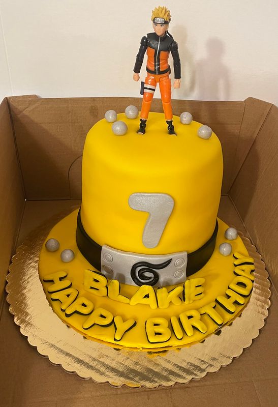 Yellow birthday cake with an anime figure on top for a 7th birthday