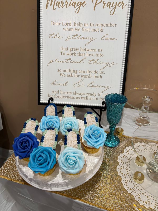 Blue rose cupcakes on a wedding table beside a marriage prayer sign