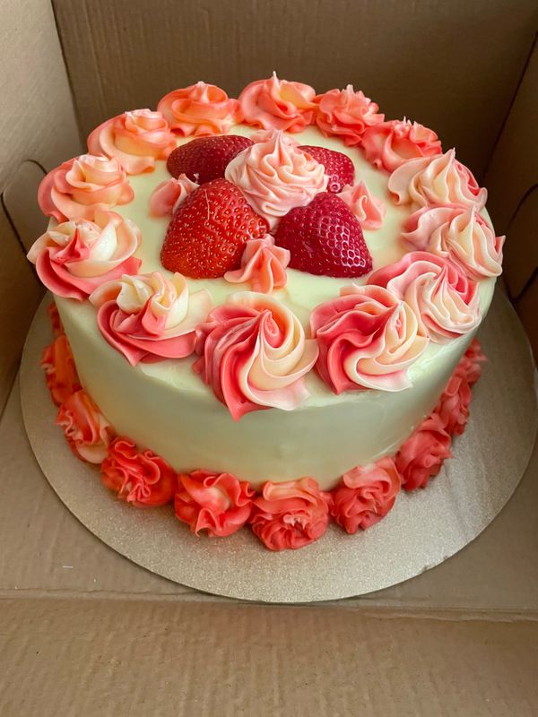 Pink and red buttercream cake topped with fresh strawberries