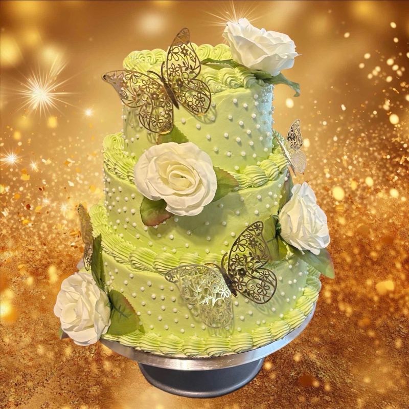 Three-tier lime green cake with white roses and gold butterflies